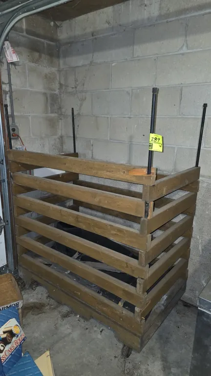 Portable wood slatted storage bin with metal corner support poles. Dimensions: 4' x 2'4" x 5'. Mounted on casters. Note: Top front slat has a chip at