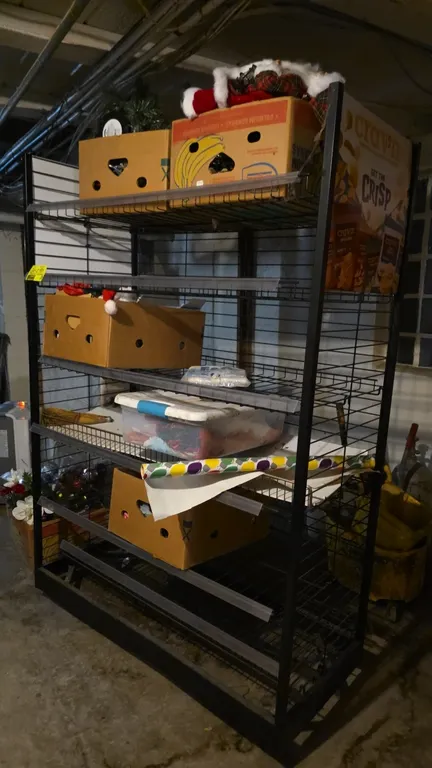5-tier portable merchandiser rack. Features black wire shelving with shelf label channels, and includes assorted holiday decorations including ornamen