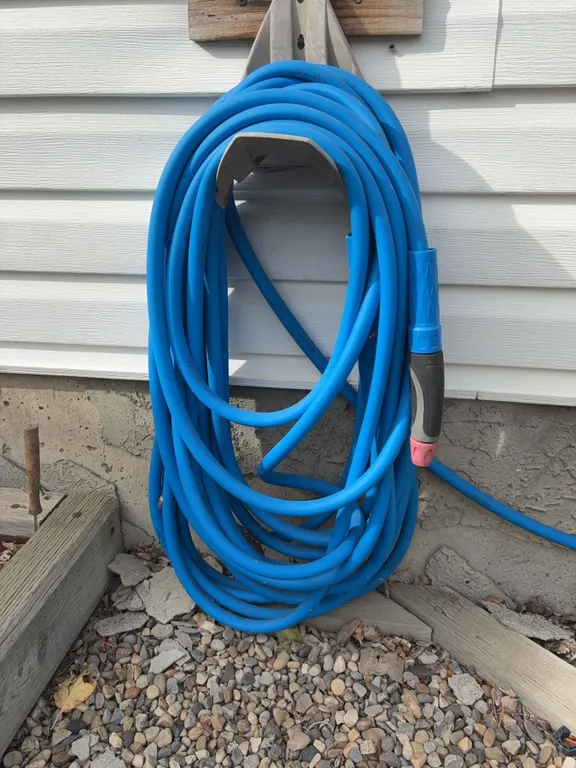 Blue Garden Hose With Spray Nozzle and Outdoor Wall Mount