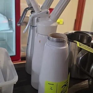 Whipped cream canisters. Includes (2) units with dispensing heads, decorating tips, and charger holders (one stainless finish, one white), and (1) whi
