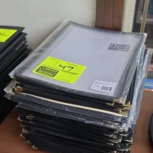 Winco PMCD-9K double-fold menu covers. Features clear panels with black trim and brass-tone metal corner protectors. Dimensions: 9-3/8" x 12-1/8".