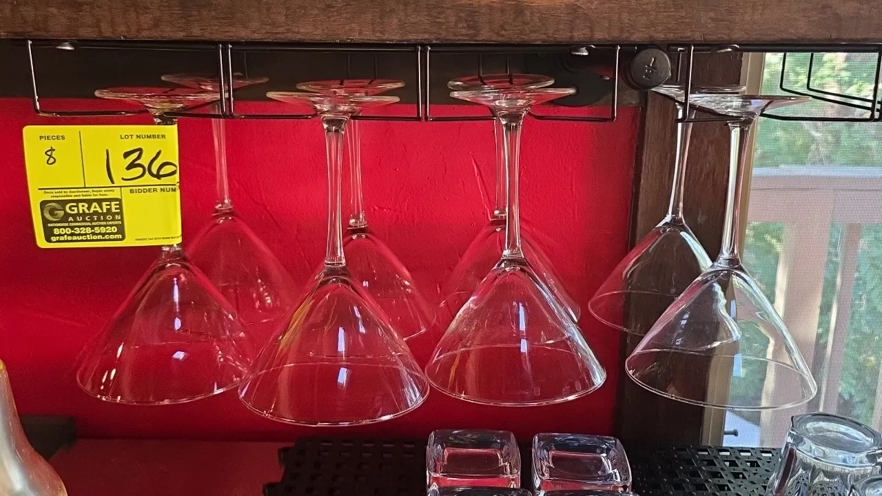 Stemmed martini glasses. Features clear glass construction with conical bowls and slender stems. Hanging rack and surrounding glassware not included.