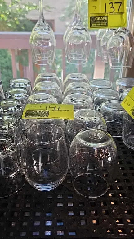 Stemless wine glasses. Features clear glass construction with a curved bowl and flat base. Surrounding glassware and drying rack not included.