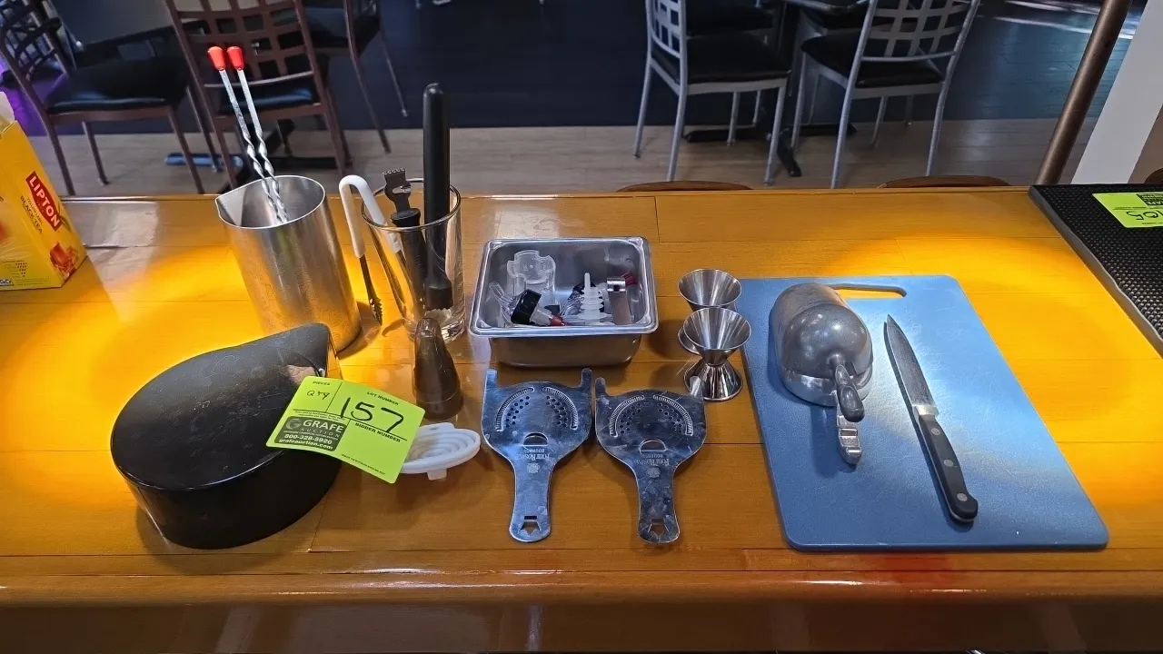 Assorted bar smallwares. Includes a plastic cutting board, paring knife, aluminum ice scoop, (2) Four Roses Hawthorne strainers, (2) stainless steel d