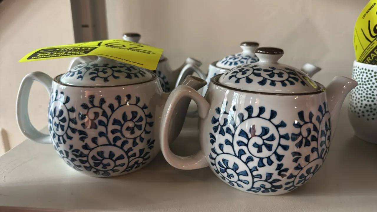 Ceramic tea infuser kettles. Features white ceramic construction with blue decorative floral scroll motifs, matching fitted lids with brown finials, s