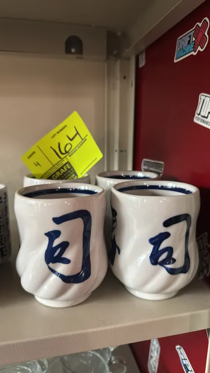 Decorative ceramic tea cups. Features white glazed ceramic construction with blue character calligraphy, spiral fluted exterior design, and blue inter