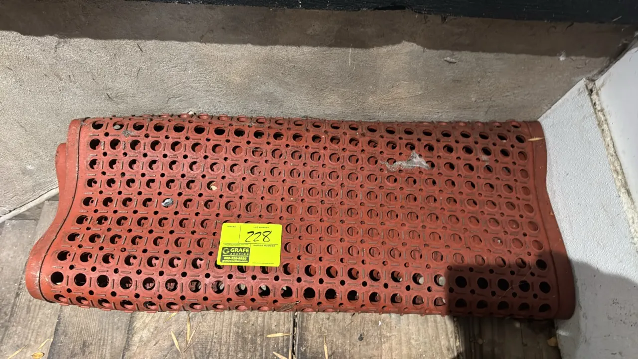 Red rubber anti-fatigue and anti-slip drainage floor mat. Features circular drainage perforations and raised traction surface. 5'L.