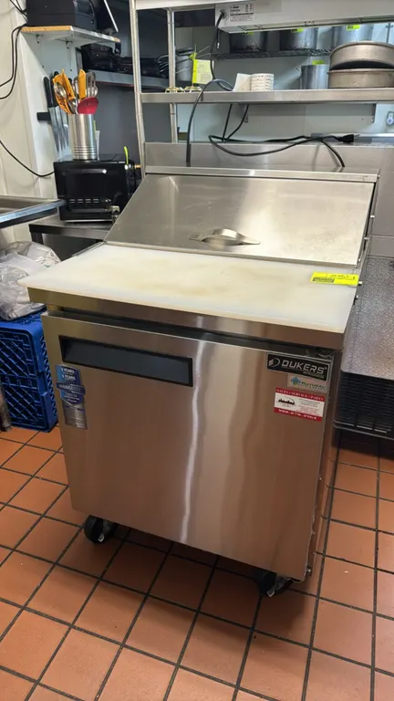 2025 Dukers DSP29 portable refrigerated prep cooler. Features stainless steel construction, hinged pan lid, prep cutting board, pan divider bars, sing