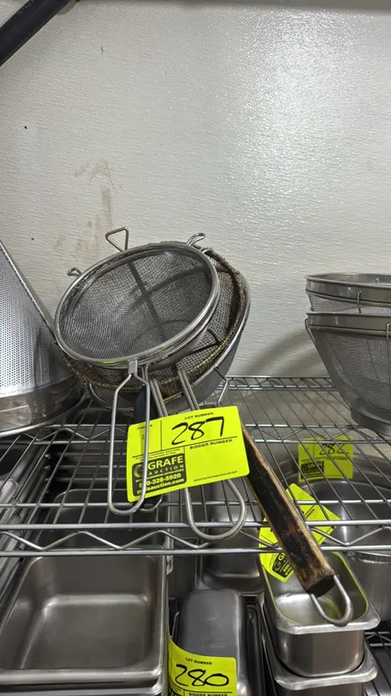 Stainless steel mesh strainers. Features assorted diameters, wire mesh construction, integrated bowl rests/support hooks, and long handles including w