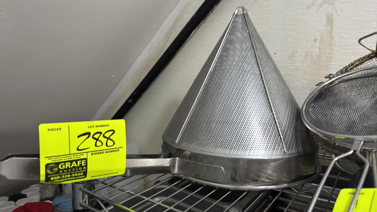 Stainless steel China cap conical strainer. Features perforated conical basket, exterior support rods, helper hook, and extended flat handle. 11" x 11