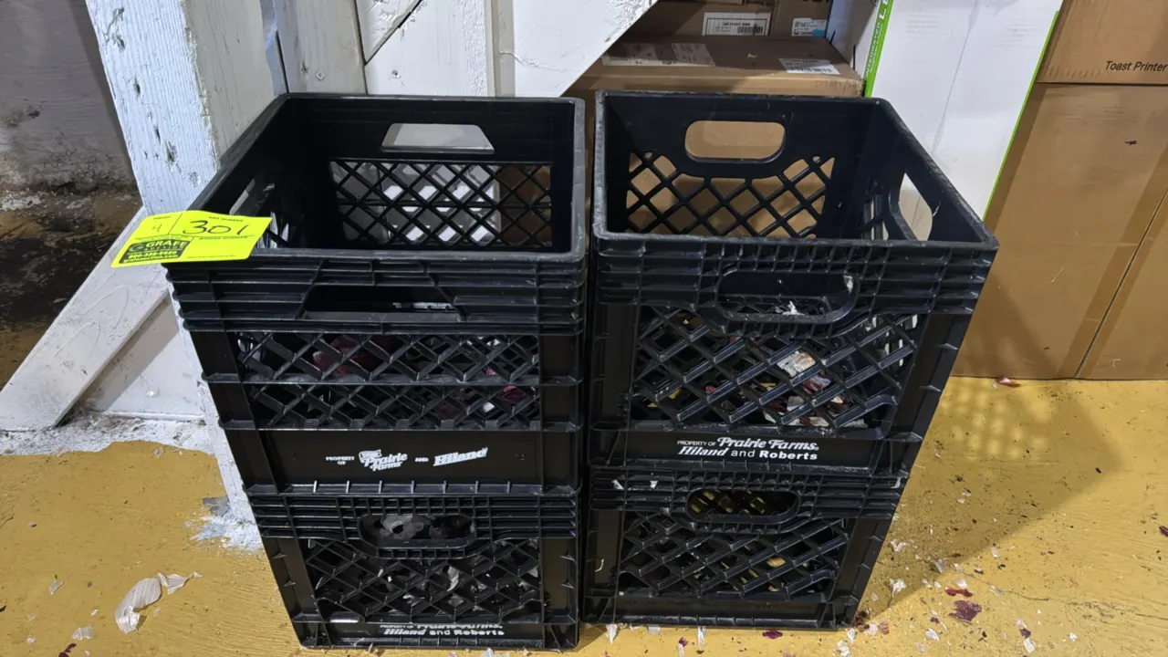 Poly milk crates. Features black molded plastic construction with open grid pattern and integrated cutout carry handles. Marked Property of Prairie Fa