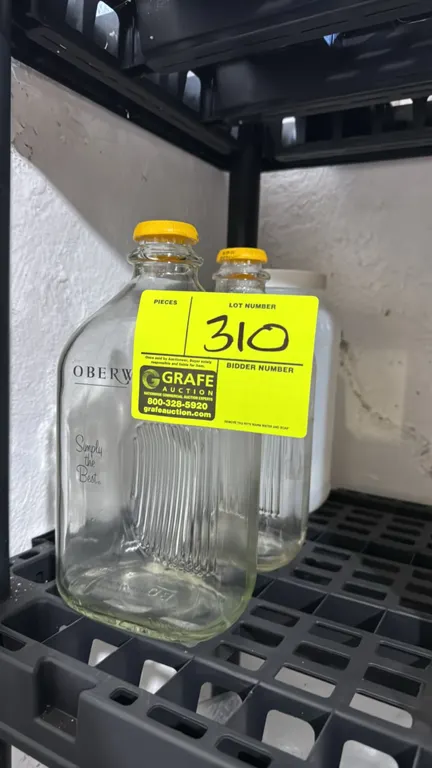 Package lot of glass and poly jugs. Includes (2) Oberweis glass milk jugs with yellow caps and (1) white polyethylene storage jug with lid.