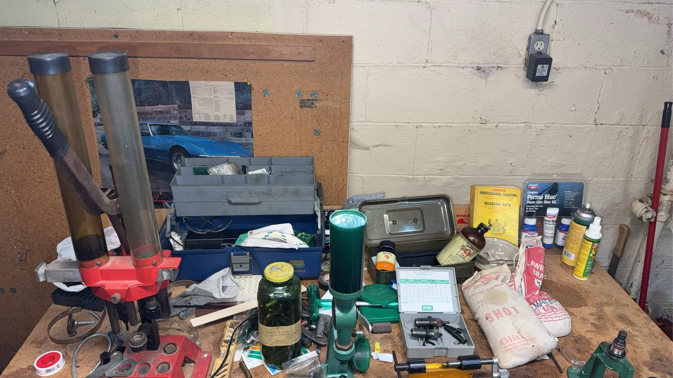 Large table full of reloading tools and presses with various cleanings kits, reloading data, and bir