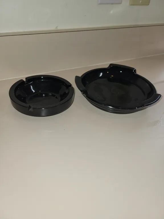 2 vintage black ashtrays. Larger one has a crack/scratch.