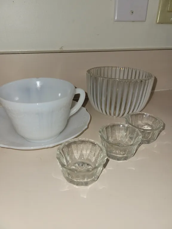 3 glass salt dishes, 1 glass dish, 1 milk glass cup with small chip on lip and a saucer.