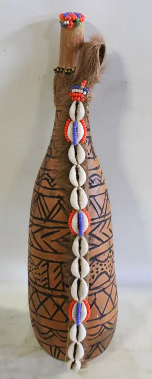 GOURD VESSEL DECORATED WITH FUR AND SHELLS.