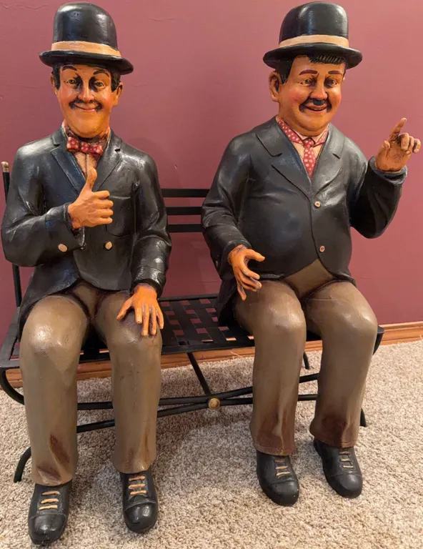 Seated Comedic Figures in Bowler Hats on Metal Bench