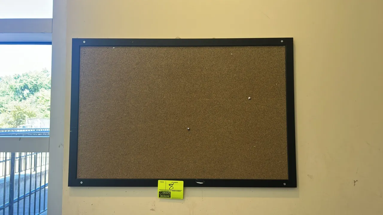 Cork bulletin board. Features a black frame and cork pin surface. Dimensions: 3' x 2'. Wall mounted.