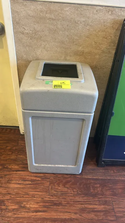 Polyethylene recycling bin. Features molded poly construction, removable top lid with square opening, and green recycling graphic. Gray finish.