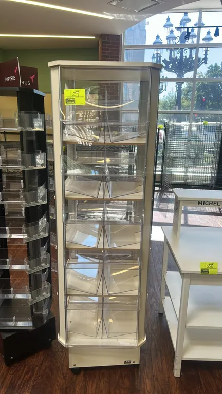 4-sided rotating display merchandiser. Features multi-tier clear acrylic display bins and laminate construction. Mounted on casters.