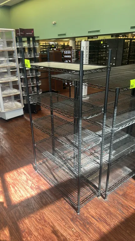 Metal wire multi-tier shelving rack. Features a 5-tier black finish design with flat wire shelves, basket-style wire shelves, and a top shelf liner. D
