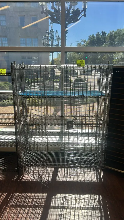 Metro multi-tier chrome wire security cage. Features double hinged front mesh doors, wire mesh sides and back, adjustable wire shelving, and a shelf l