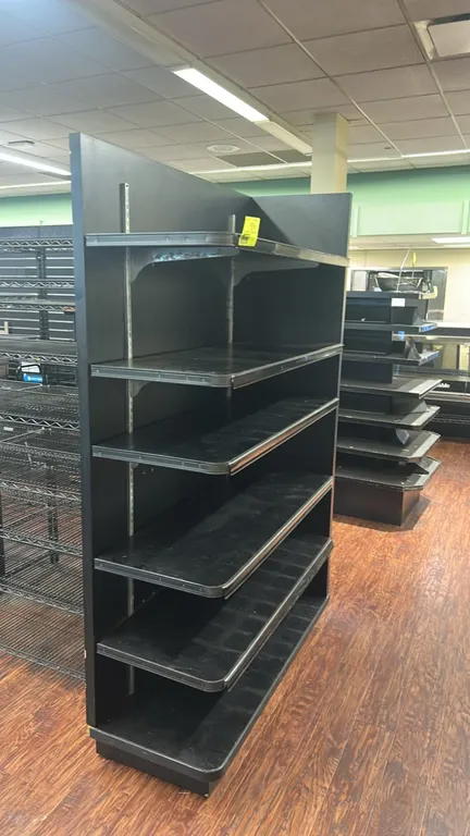 Laminate multi-tier merchandising shelf. Features black finish, (5) adjustable upper shelves, (1) base shelf, metal slotted upright standards, and she