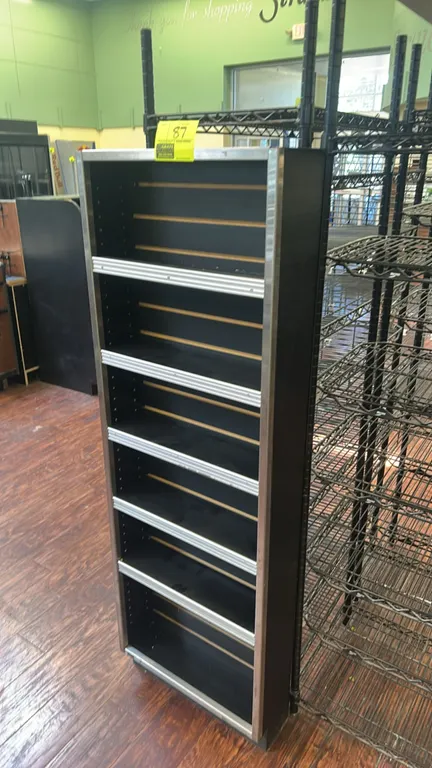 Laminate multi-tier display merchandiser. Features six tier shelves with integrated front ticket moldings, slatwall back panel, and metal protective e