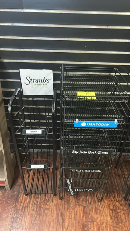 Metal wire merchandising display racks. Includes (1) multi-tier newspaper display rack with labeled shelf fronts and (1) tiered retail merchandiser wi