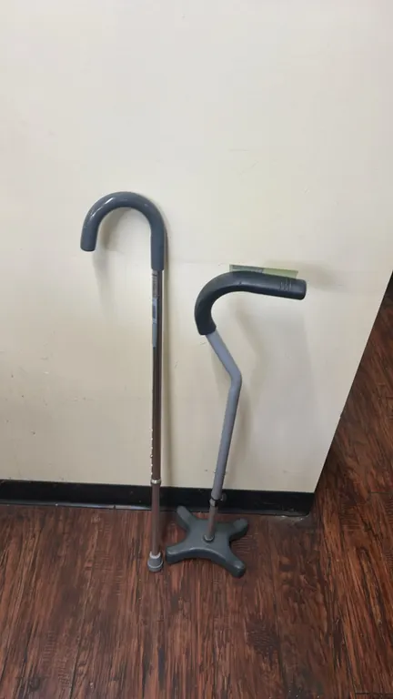 Metal walking canes. Includes one curved crook cane with single rubber tip and one offset handle cane with molded quad base. Both feature push-button