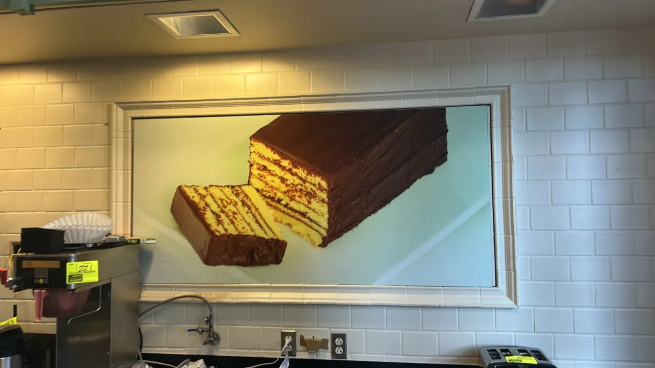 Quantity of assorted store decor. Includes (5) framed department food display signs featuring cake, charcuterie board, chicken salad, chili, and slice