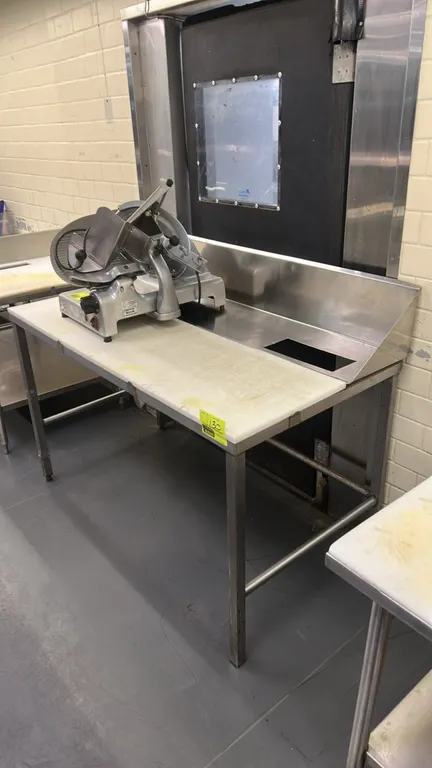 Stainless steel prep table. Features poly cutting board top, rear stainless steel backsplash with upper shelf, integrated cutout, and stainless steel