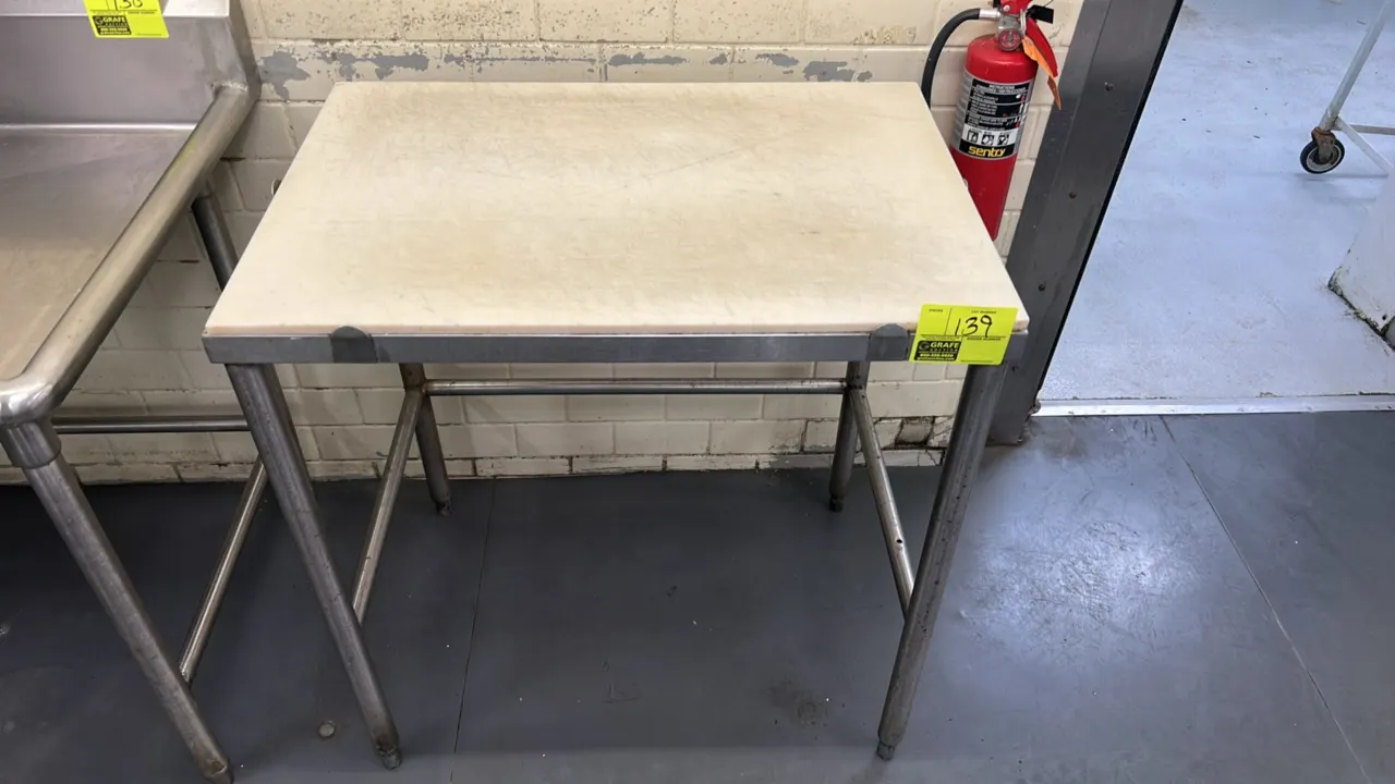 Stainless steel work table with poly top. Features tubular legs with cross-bracing and adjustable bullet feet. 34" x 24".
