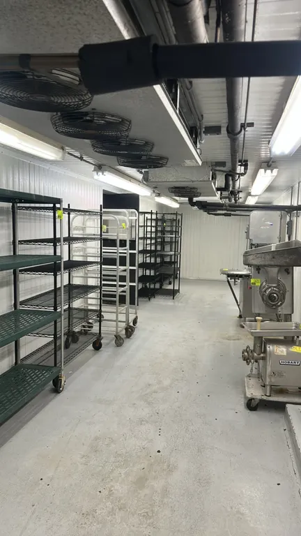 Foam panel walk-in cooler. Features (3) Hussmann 2-fan evaporator coils, (1) Hussmann 4-fan evaporator coil, overhead lighting, (2) poly swing doors,