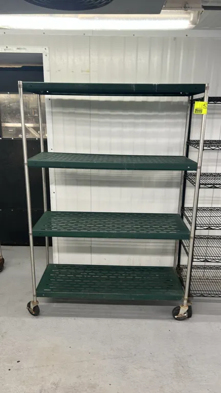 Metal 4-tier portable shelving rack. Features (4) green slotted shelves and metal upright posts. 48" x 18". Mounted on swivel casters.