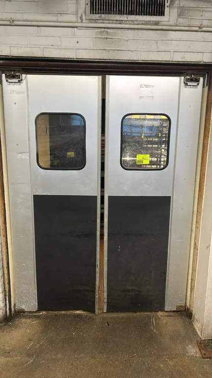 Aluminum swing doors. Features clear view windows, lower black impact kick plates, and top pivot hardware. 29"W x 79"H each.