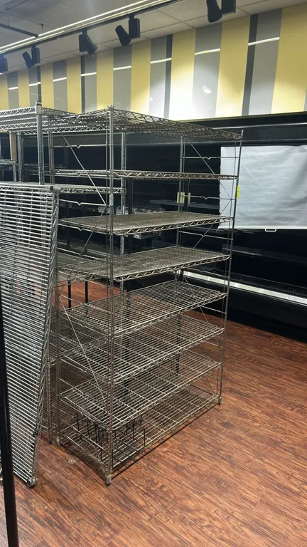 Metal wire multi-tier shelving rack. Features (7) wire shelves. Dimensions: 42" x 18". Mounted on stationary leveling feet.