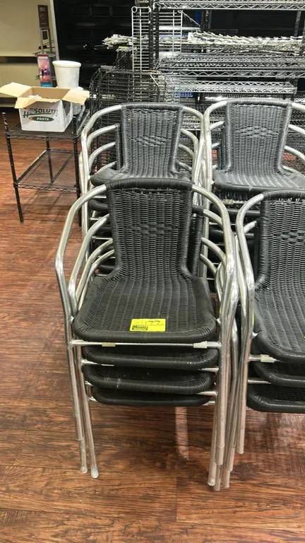 Metal and wicker outdoor stacking armchairs. Features lightweight aluminum frames with integrated armrests and black woven synthetic wicker seating an