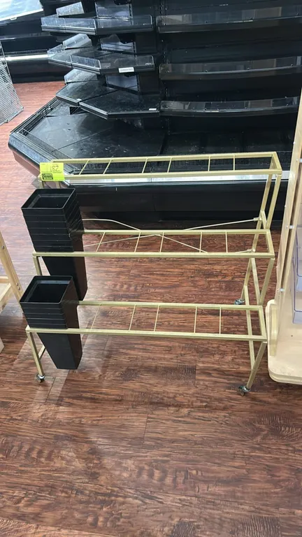Metal 3-tier portable floral merchandiser display rack. Features tiered gold-tone metal frame construction with vase holder compartments and includes