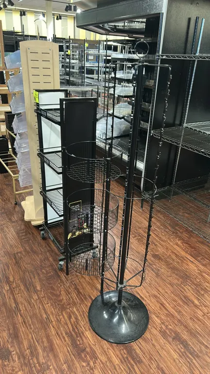 Metal wire multi-tier display merchandisers. Includes a 4-tier mobile shelf rack on casters with side panels, a 3-tier round wire basket display stand