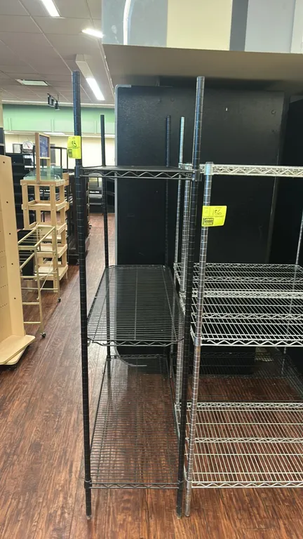 Metro 3-tier metal wire shelving rack. Features (3) adjustable wire shelves with a black finish. Dimensions: 48" x 18". Adjacent shelving and backgrou