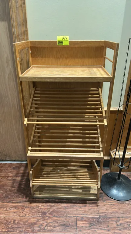 Wooden multi-tier bakery merchandiser. Features wood construction, flat upper shelf with raised border, and three slanted slatted display shelves. 28"