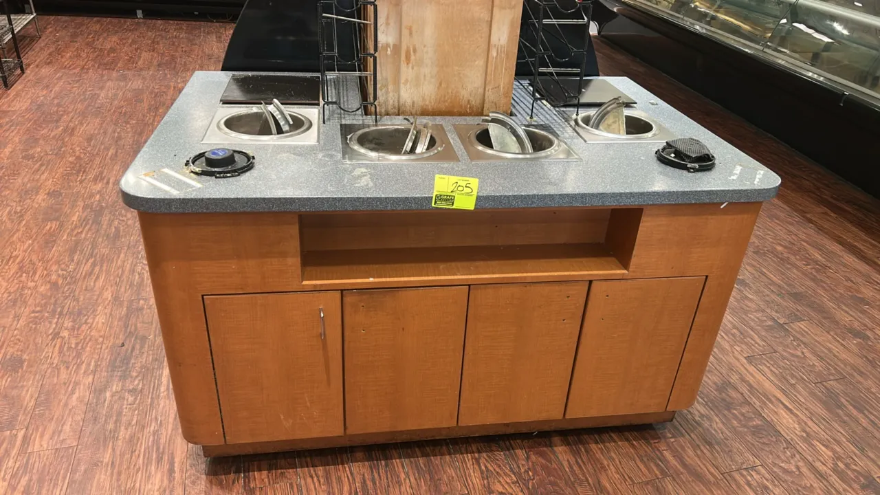 Laminate soup bar. Features a solid surface countertop, (6) drop-in soup wells with stainless steel hinged lids, wire dispenser racks, an open storage