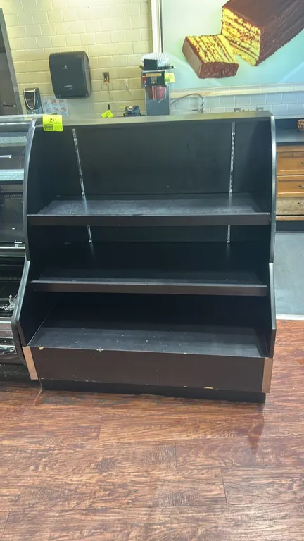 Laminate multi-tier merchandiser display. Features black laminate construction, 3-tier presentation with two adjustable upper shelves, slotted metal s