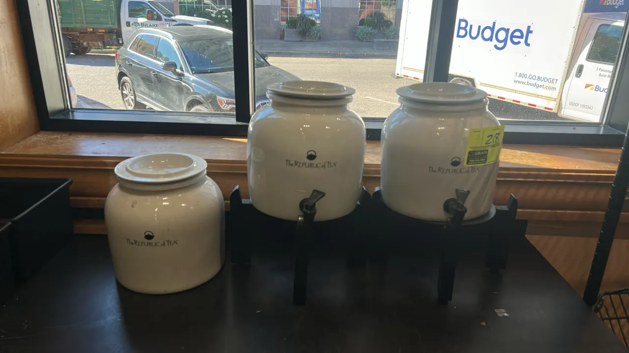 The Republic of Tea ceramic beverage dispensers. Features white glazed ceramic bodies with matching lids. Includes (2) dispensing spigots and (2) blac