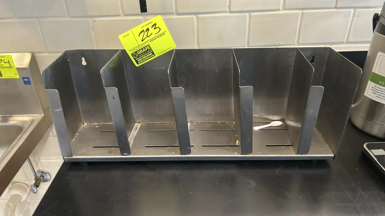 Stainless steel 4-compartment lid organizer. Features a slotted base and keyhole mounting slots for wall hanging or countertop use.