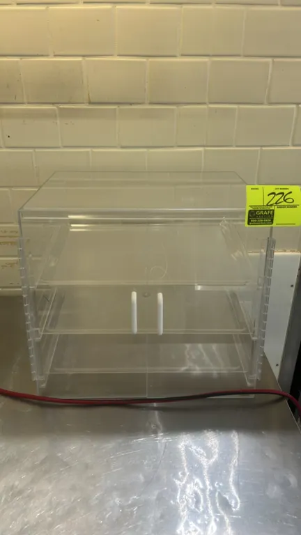 Polycarbonate countertop bakery display case. Features clear acrylic construction, 3 tiers with removable clear display trays, and dual hinged doors w