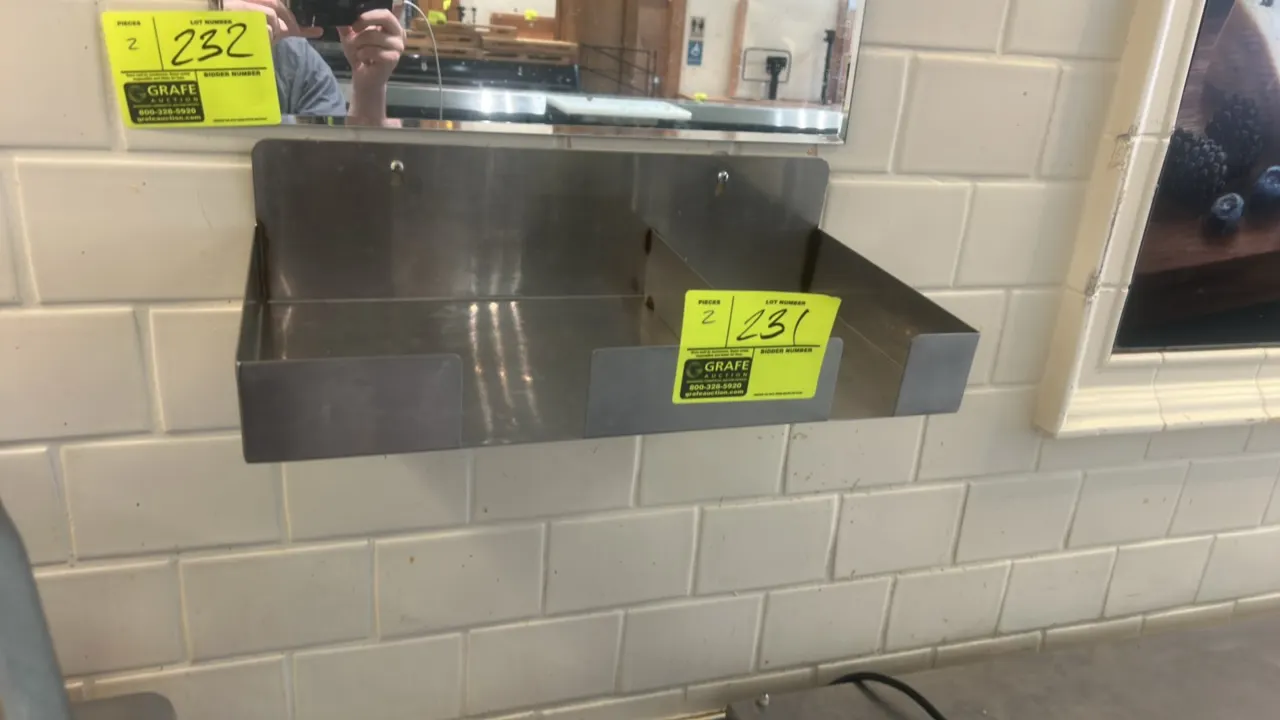 Stainless steel wall-mounted shelves. Features dual divided compartments, front retaining lips, and integrated keyhole wall-mounting slots.