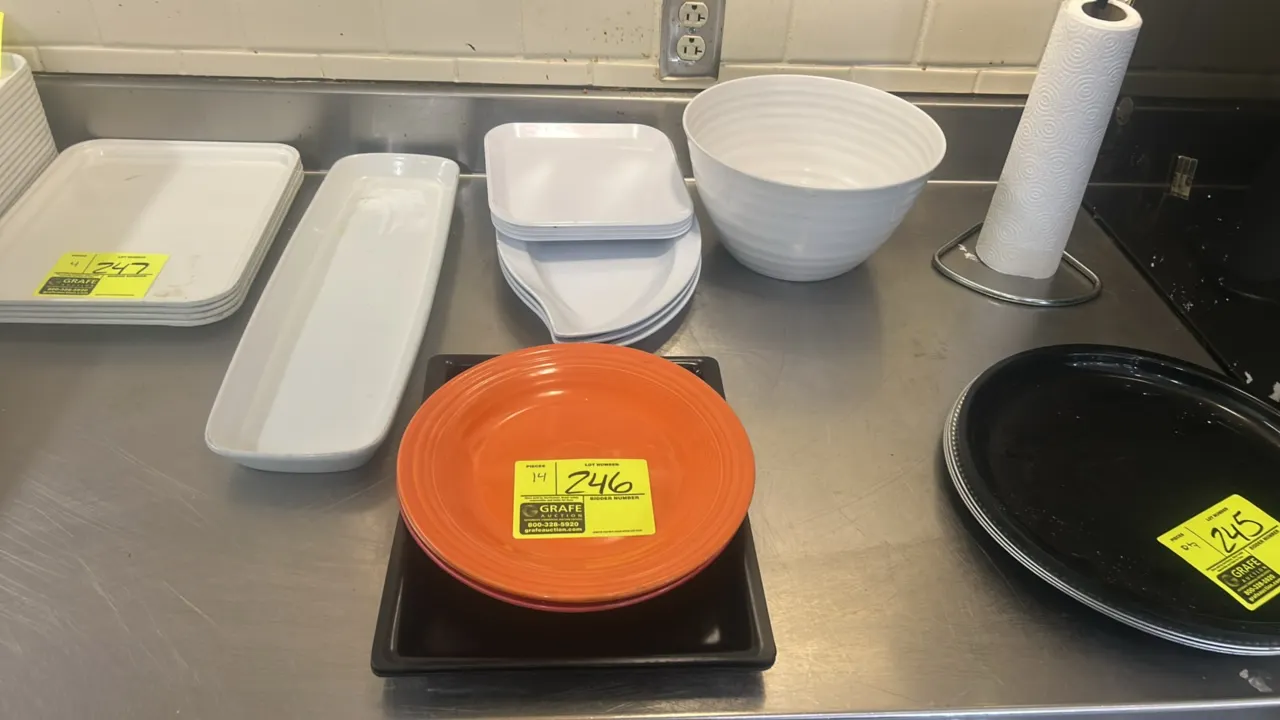 Assorted ceramic and polymer display and servingware. Includes round plates, rectangular display trays, elongated and curved platters, and a large rib