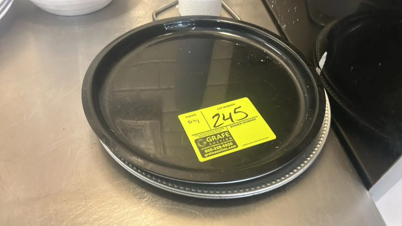 Assorted plastic plates and chargers. Includes black round display platters and silver-tone beaded rim charger plates.